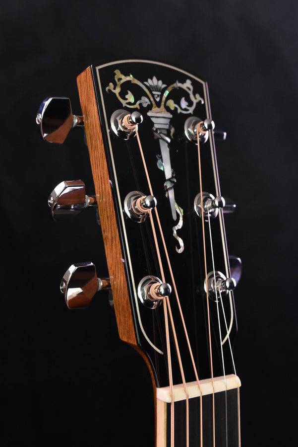 Guitar headstock close-up with vine-style inlay and tuning pegs