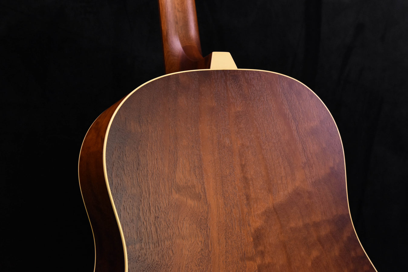 Guitar top with dark wood grain and cream binding around sound hole