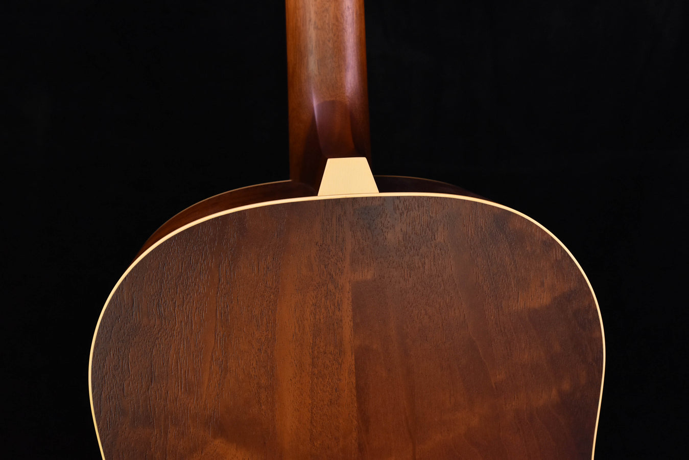 Guitar top panel with swirling dark wood grain and cream edge binding