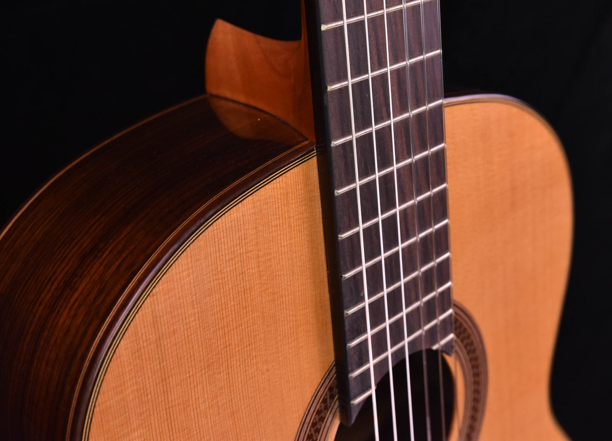 Classical guitar neck close-up with frets and edge of the cedar top