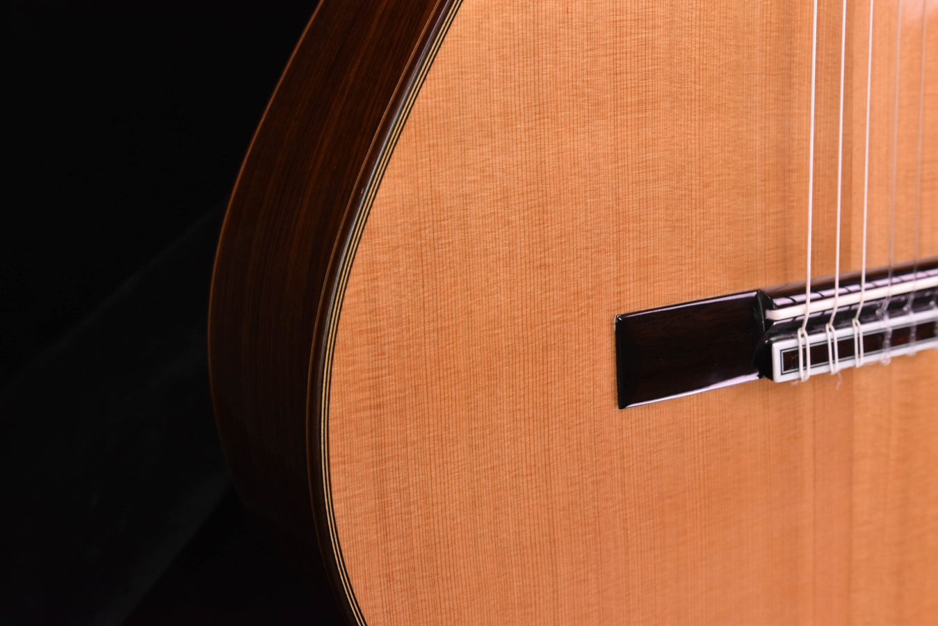 Cedar top classical guitar bridge area with strings and saddle