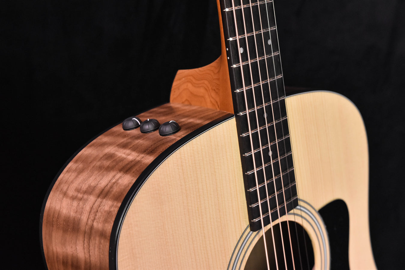 Guitar neck and headstock with warm wood grain and tuning pegs visible