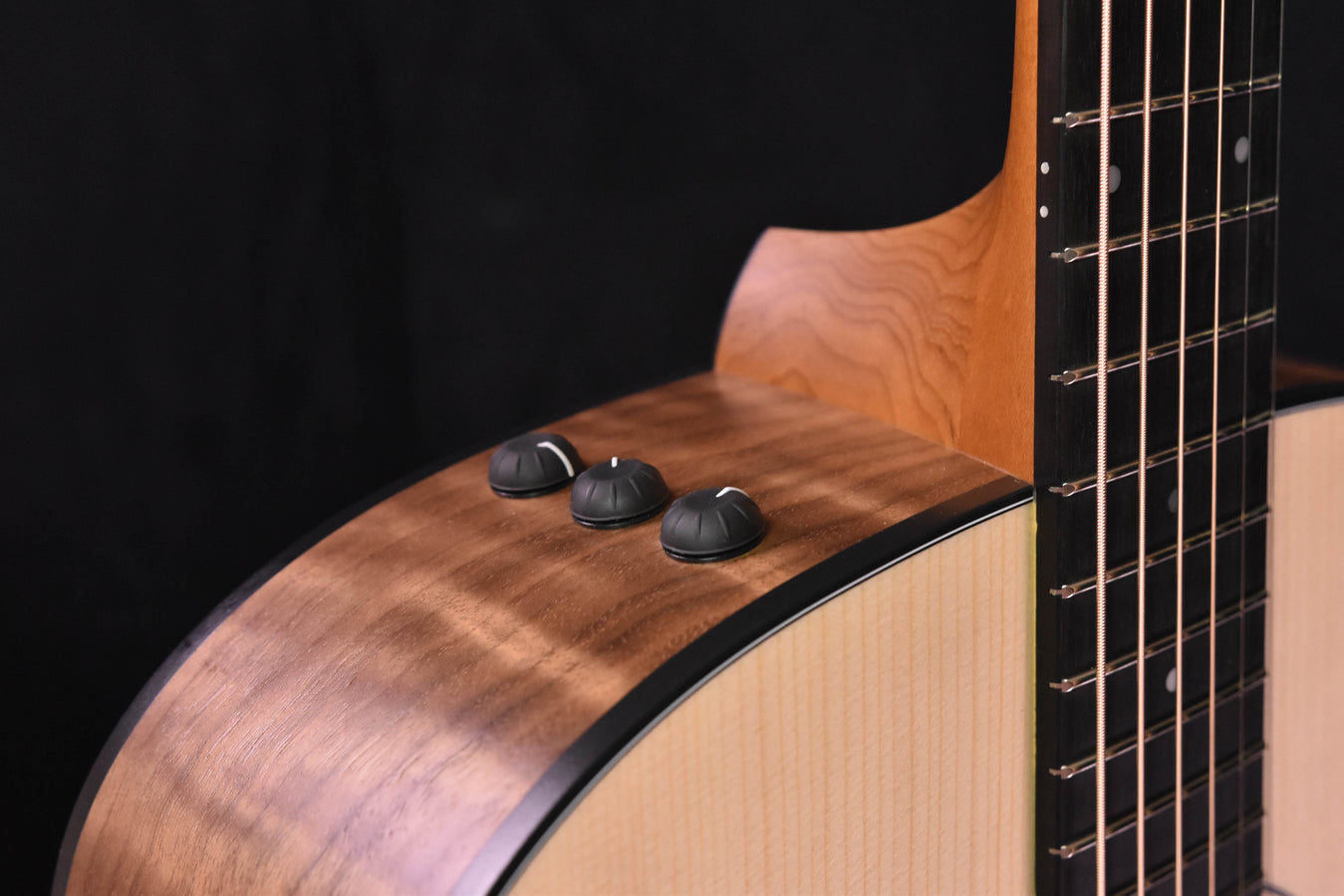 Acoustic-electric top with three black control knobs and visible strings