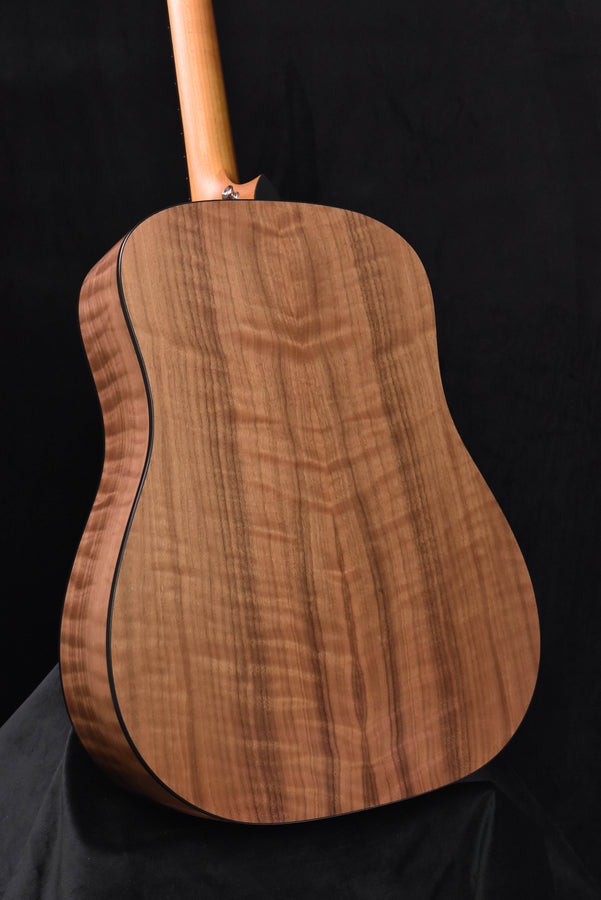 Acoustic guitar back panel with warm wood grain and neck heel visible