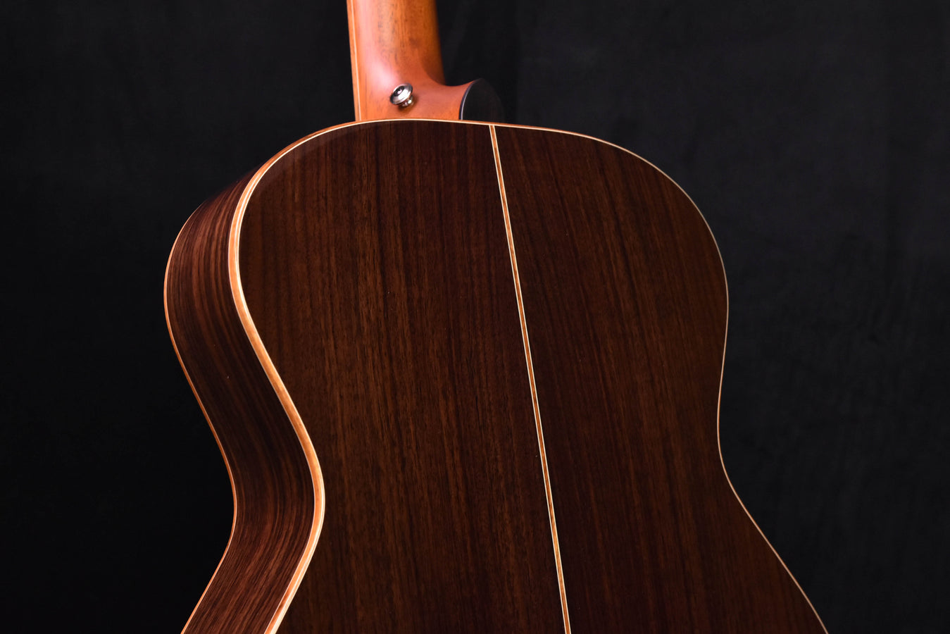 Used acoustic guitar back view showing rich dark wood grain along the center seam
