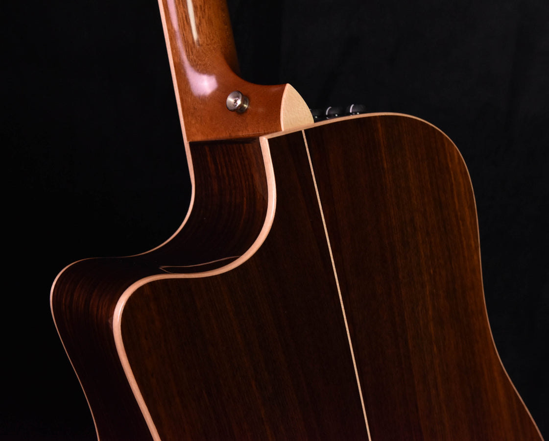 Used acoustic guitar side close-up: neck joint and glossy dark wood with binding