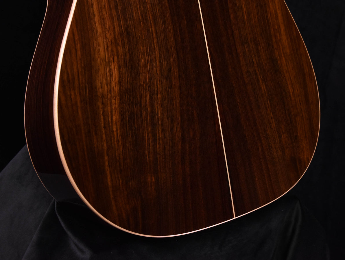 Used acoustic guitar close-up of lower body: dark wood grain and curved edge binding