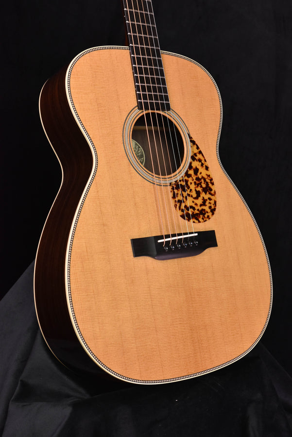 Acoustic guitar front view with light wood top, decorative rosette, and tortoiseshell pickguard
