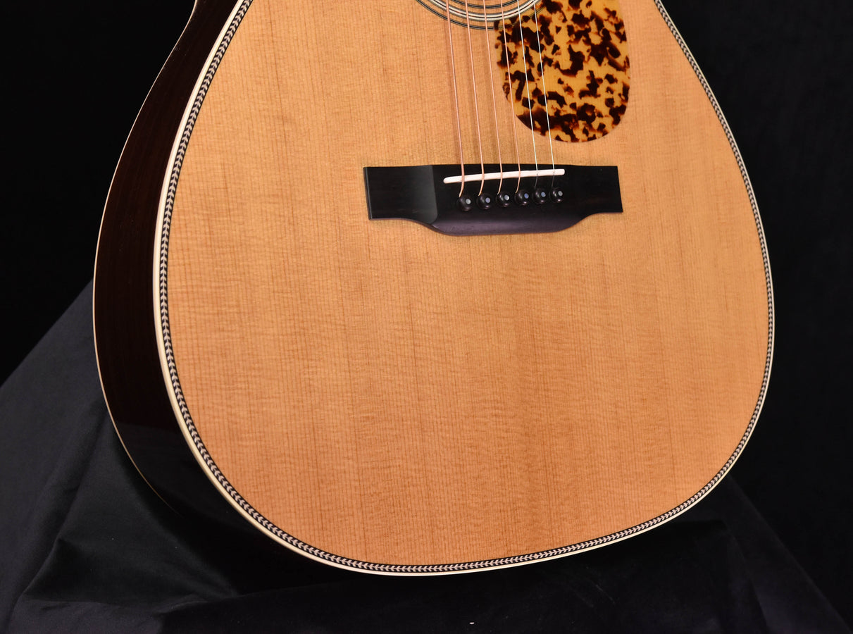 Acoustic guitar body close-up with bridge area, light top, and tortoiseshell pickguard