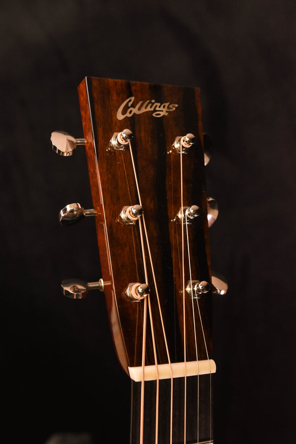 Acoustic guitar headstock with tuning pegs and engraved brand logo
