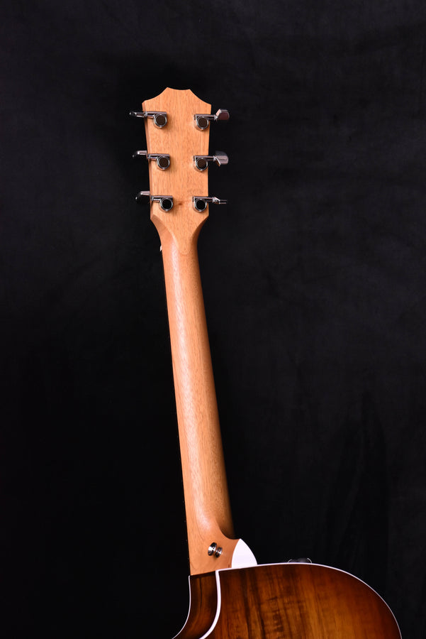 Guitar headstock with six chrome tuning pegs on natural wood