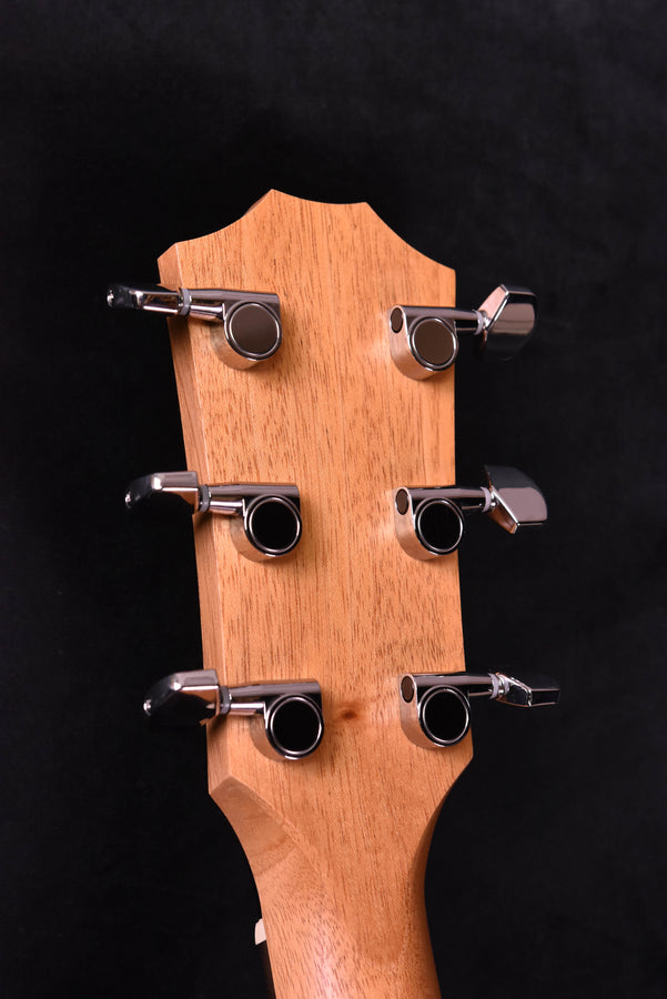 Guitar headstock close-up with six tuning pegs, natural wood finish