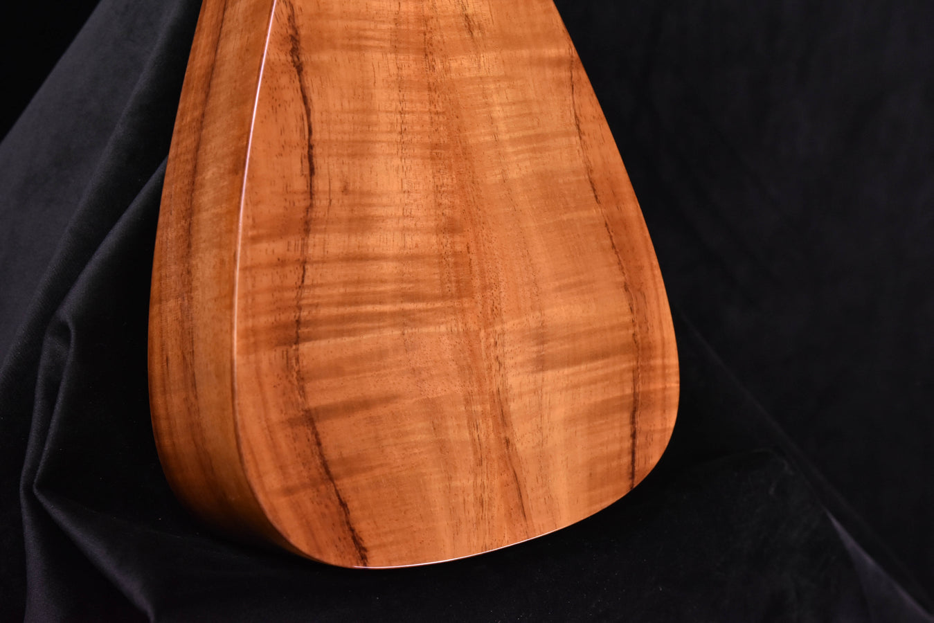 Koa tenor ukulele body close-up showing fine grain and tapered lower bout