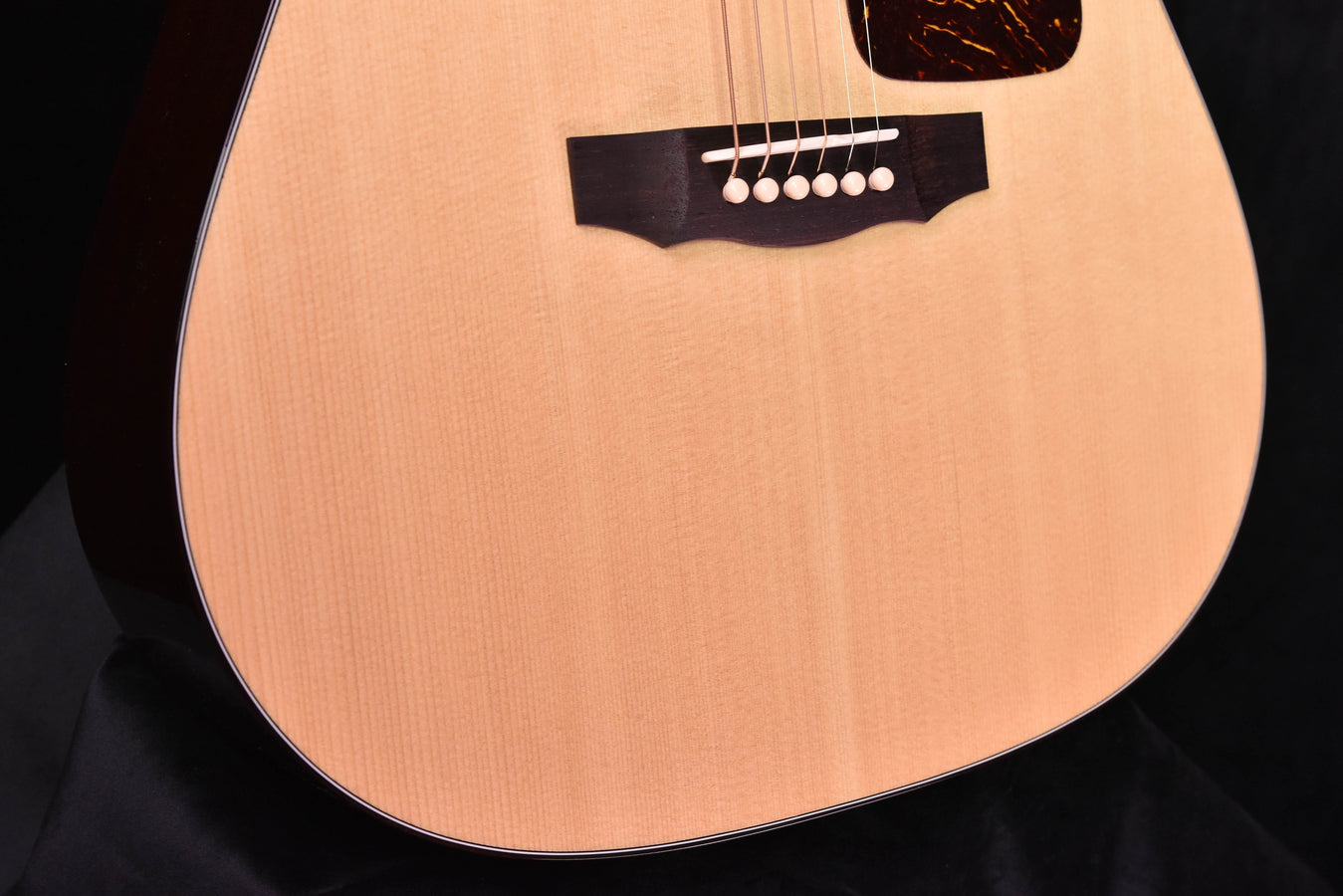 Natural-finish dreadnought acoustic guitar, black pickguard and strings shown
