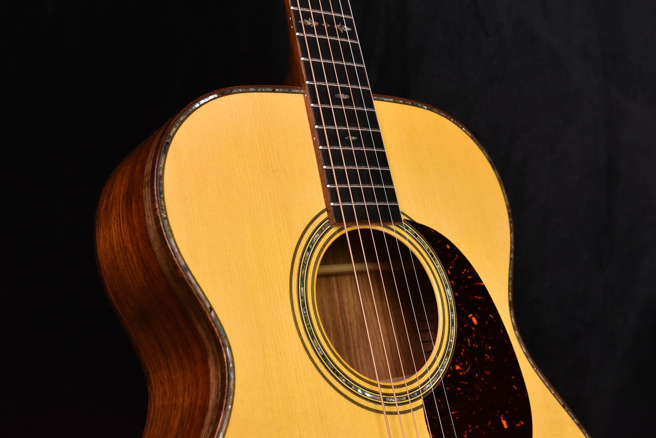 Acoustic guitar sound hole and rosette with fretboard, strings, and dark pickguard