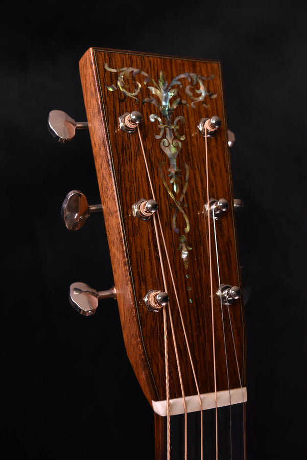 Acoustic guitar headstock with ornate inlay, chrome tuning keys, and nut area