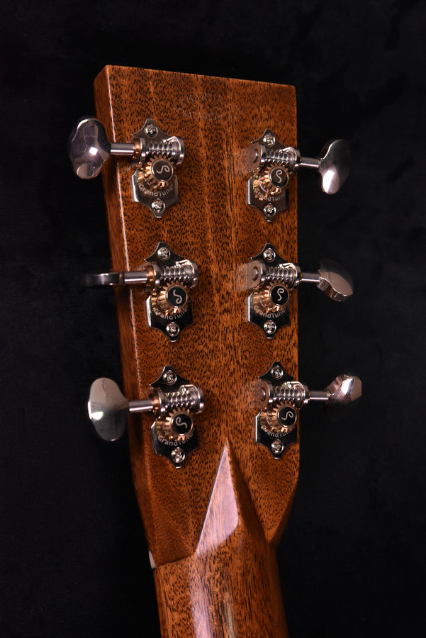 Acoustic guitar headstock close-up showing tuning machines with engraved plates