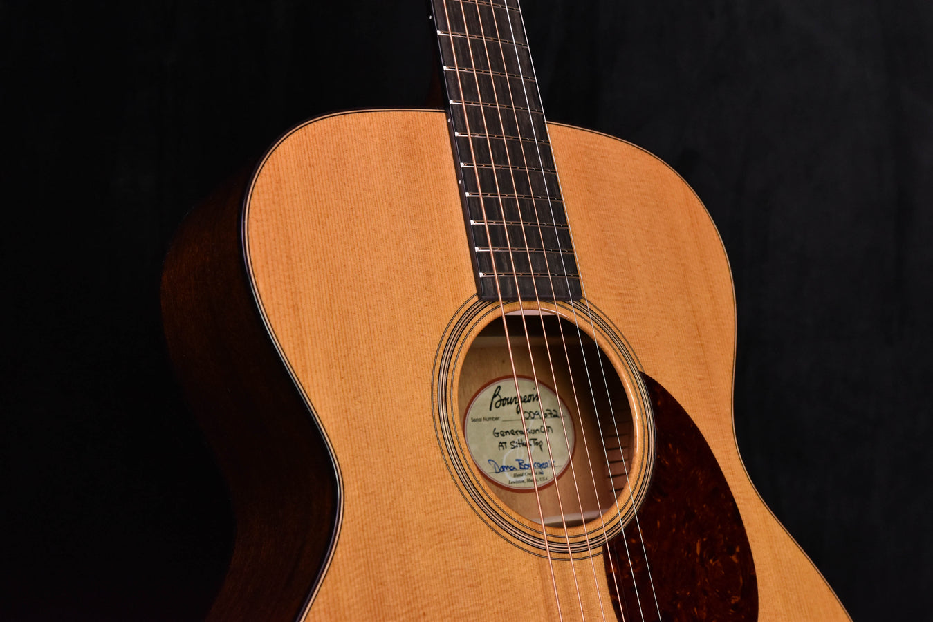 Acoustic guitar soundhole area with rosette and strings on natural wood top.