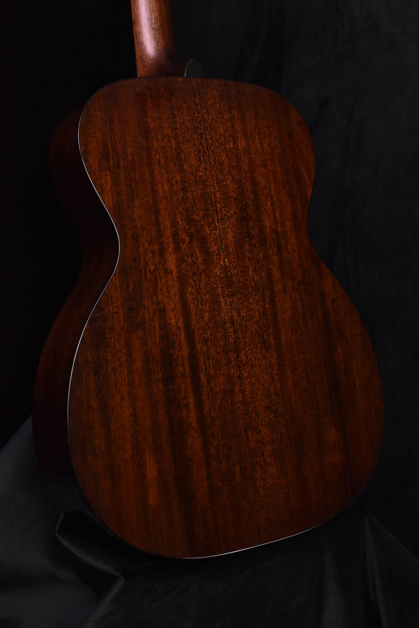 Acoustic guitar back view with textured wood grain in dark aged tone.