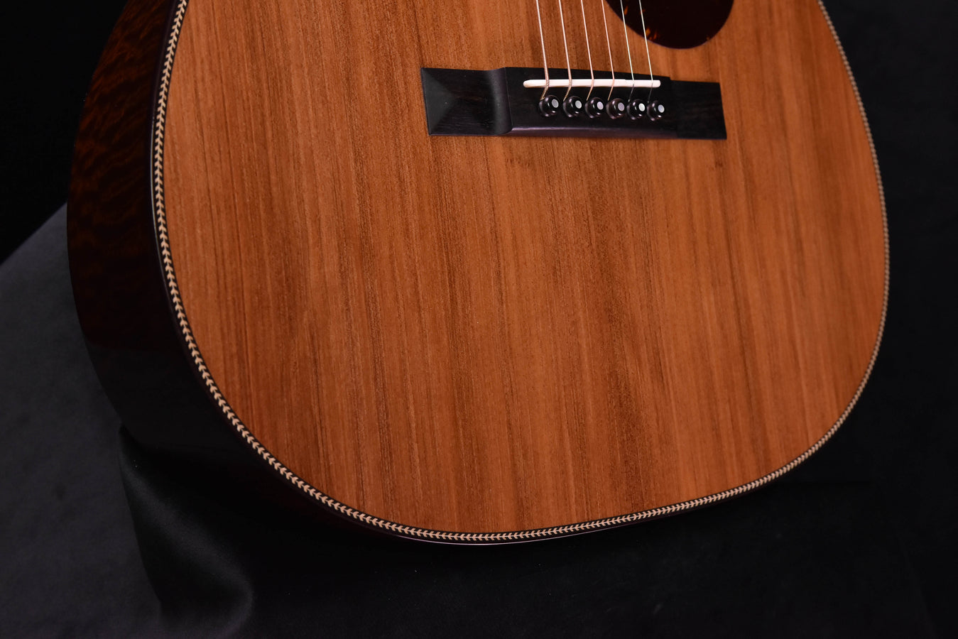 Acoustic guitar lower bout and bridge, natural wood top and black bridge plate