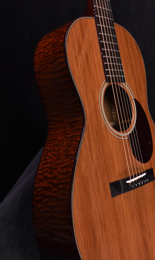 Acoustic guitar angled side view, natural front and quilted back with binding
