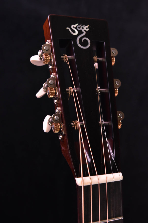 Headstock close-up with “6” inlay, gold tuning pegs and white nut