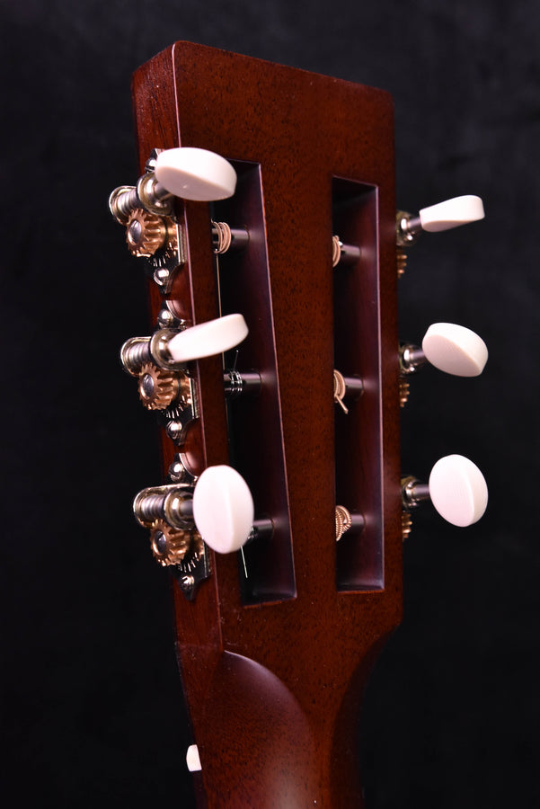 Acoustic guitar headstock with tuning pegs and dark wood finish, close-up