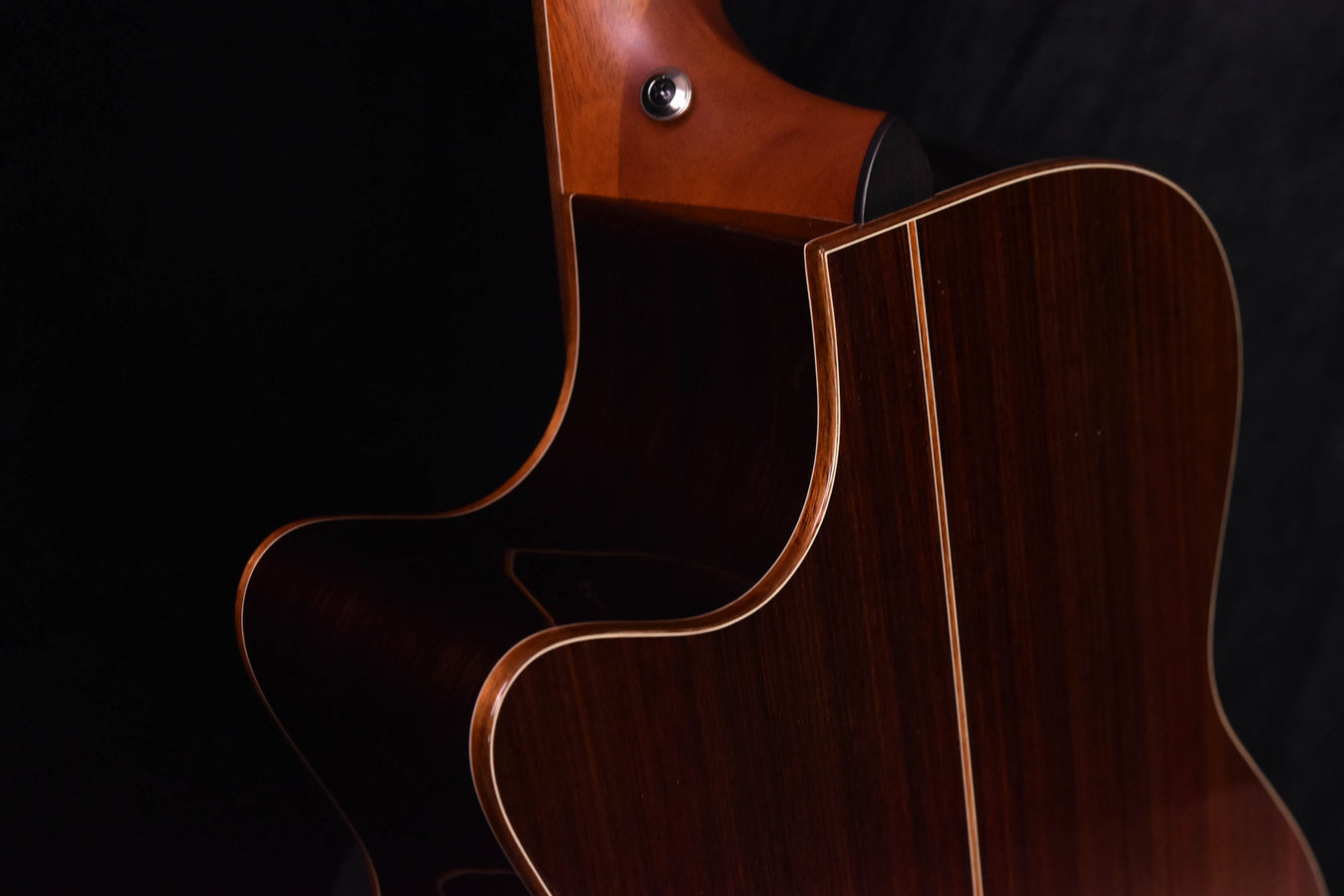 Upper bout and soundhole area of red-brown cutaway acoustic guitar
