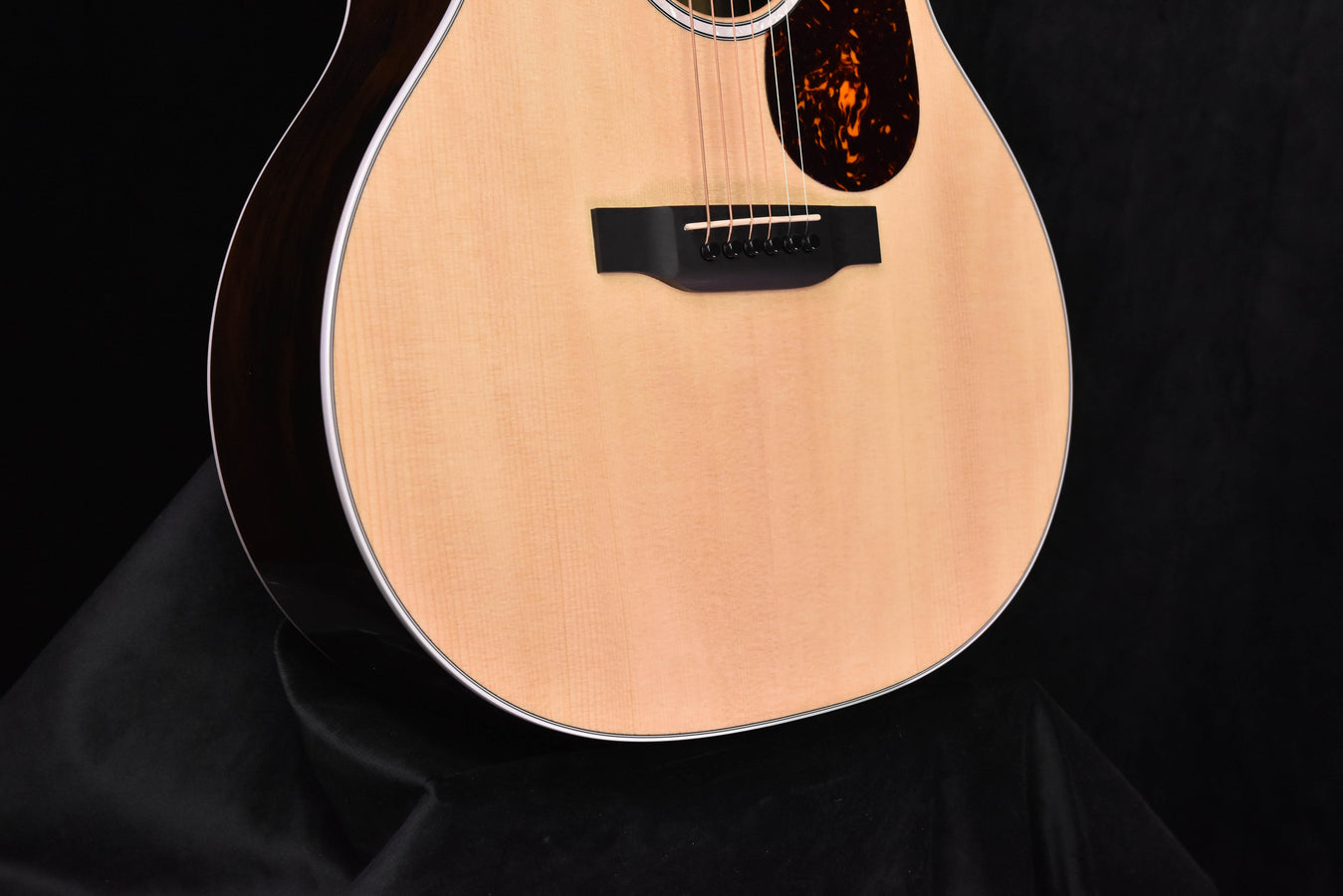 Acoustic-electric guitar front view, dark pickup area on light wood top