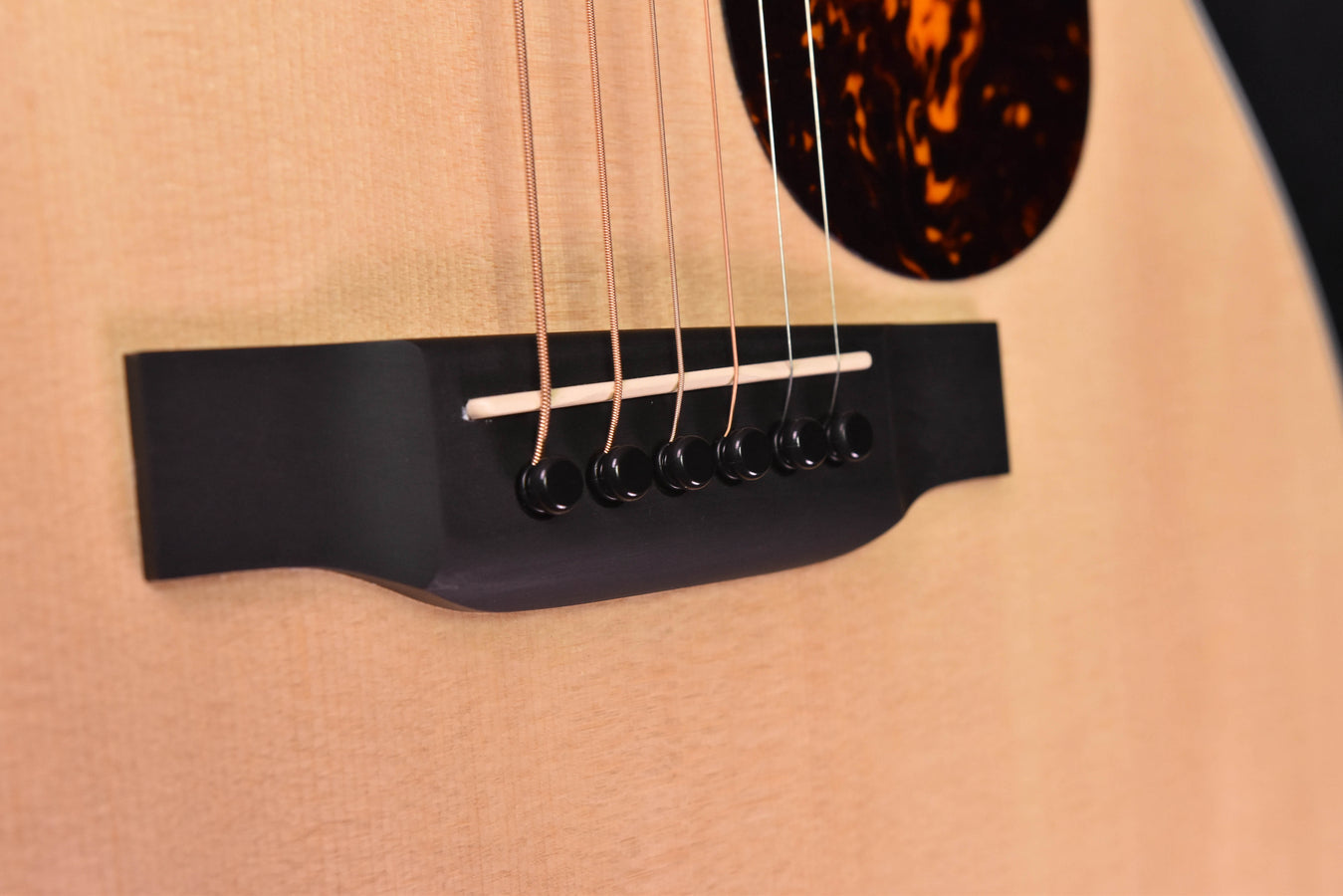 Acoustic-electric guitar pickup and strings over dark pickguard