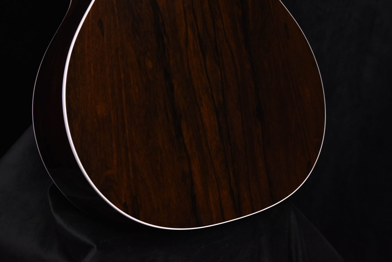 Acoustic-electric guitar top close-up with dark wood grain and white edge binding