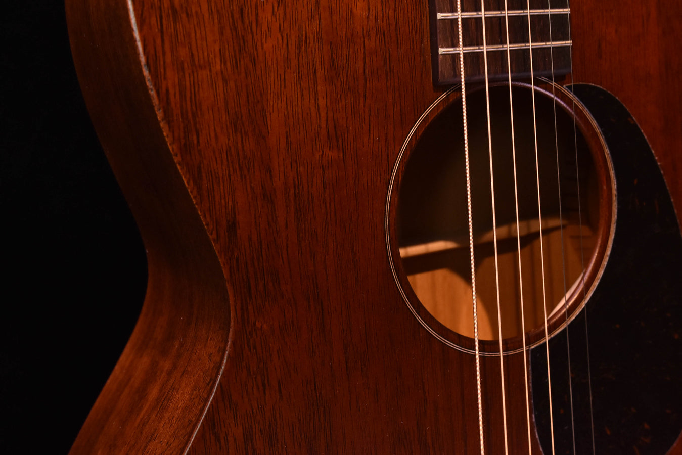 Close view of the acoustic guitar soundhole and strings over the mahogany top