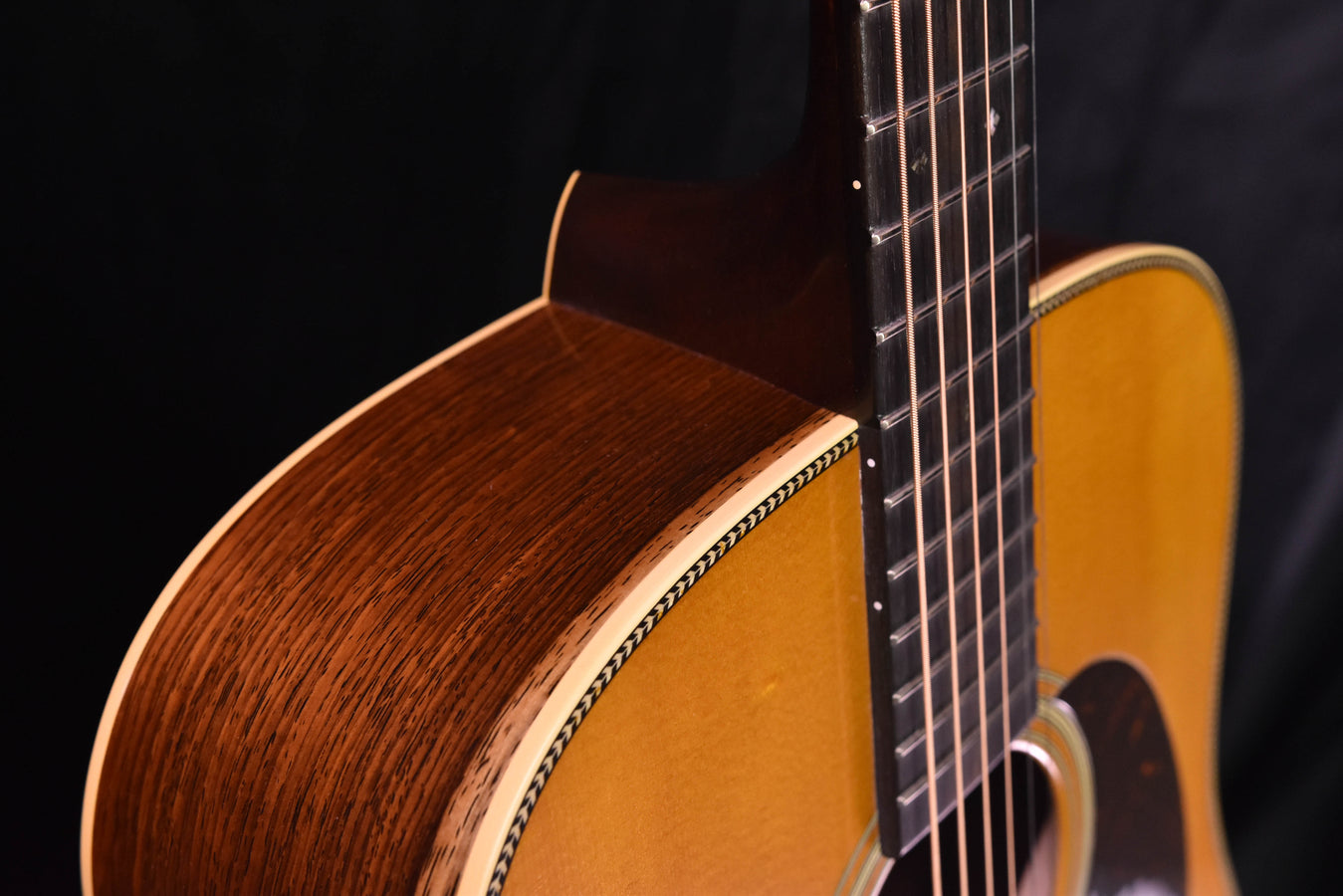 Acoustic guitar neck and body joint close-up with dark rosewood sides and bound top