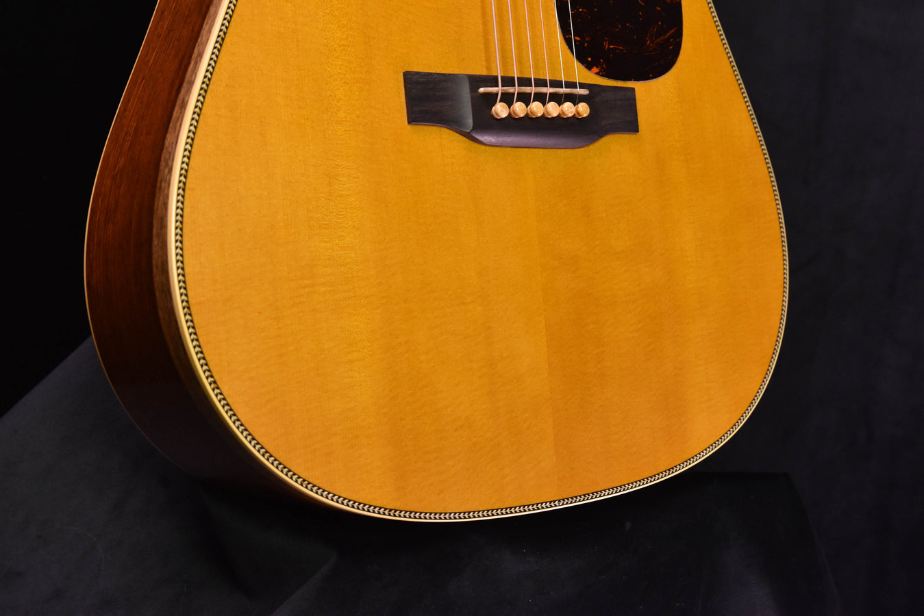 Tortoiseshell pickguard with bridge and strings on a natural dreadnought acoustic guitar
