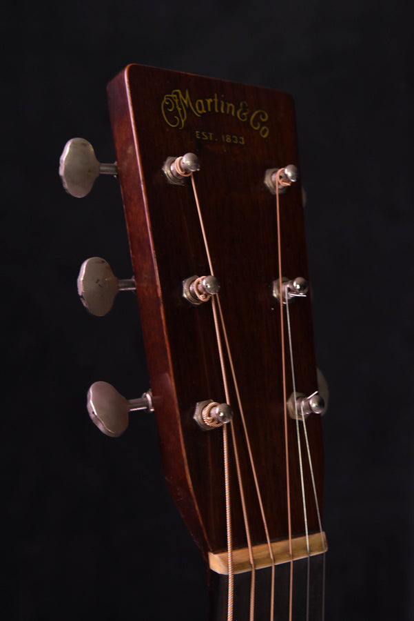 Headstock close-up showing tuning pegs and gold script logo on dark wood