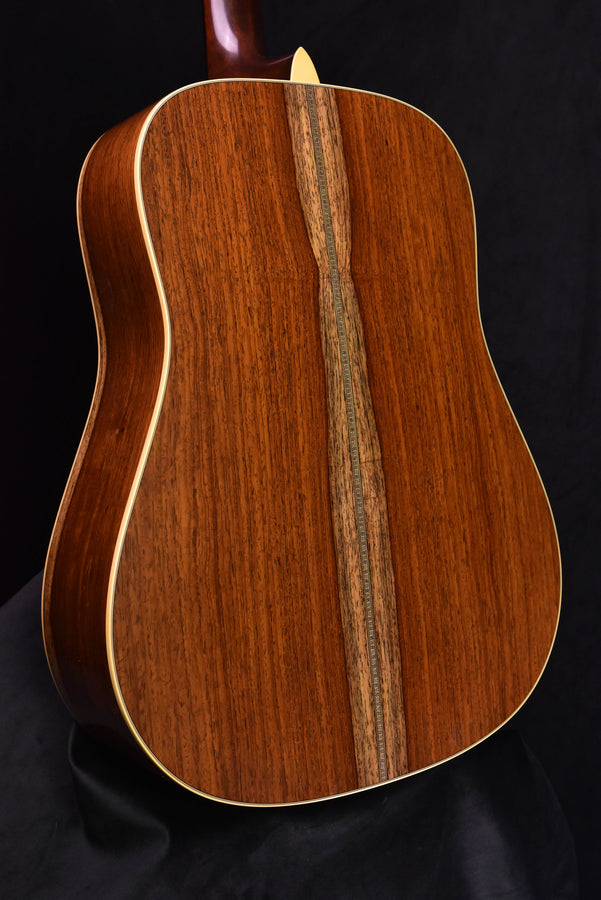 Close-up of acoustic guitar back with vertical dark center stripe and glossy natural finish