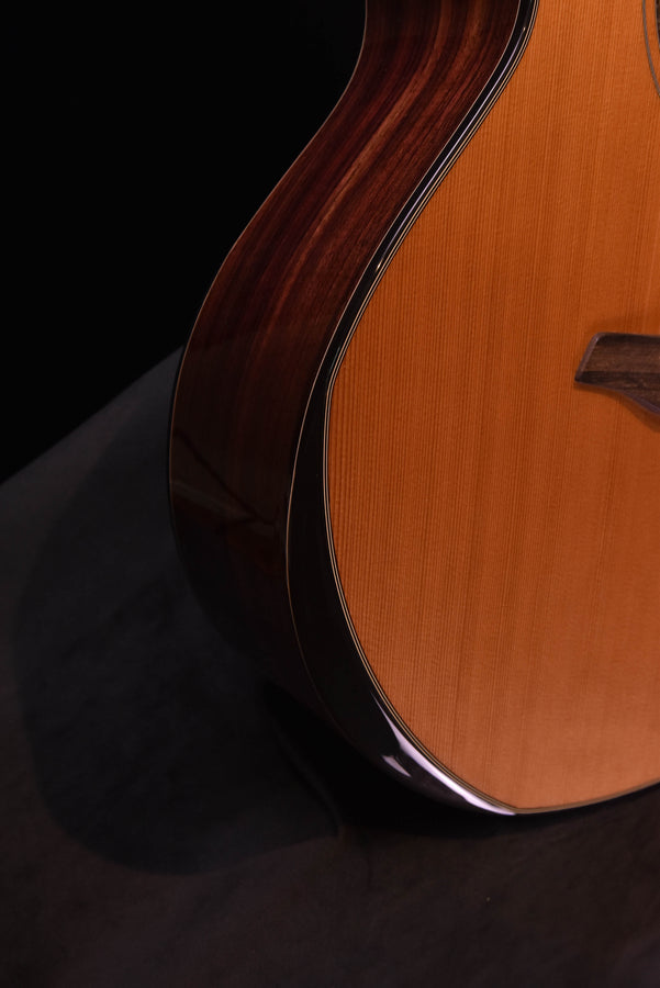 Side view of yellow acoustic cutaway guitar body with dark binding