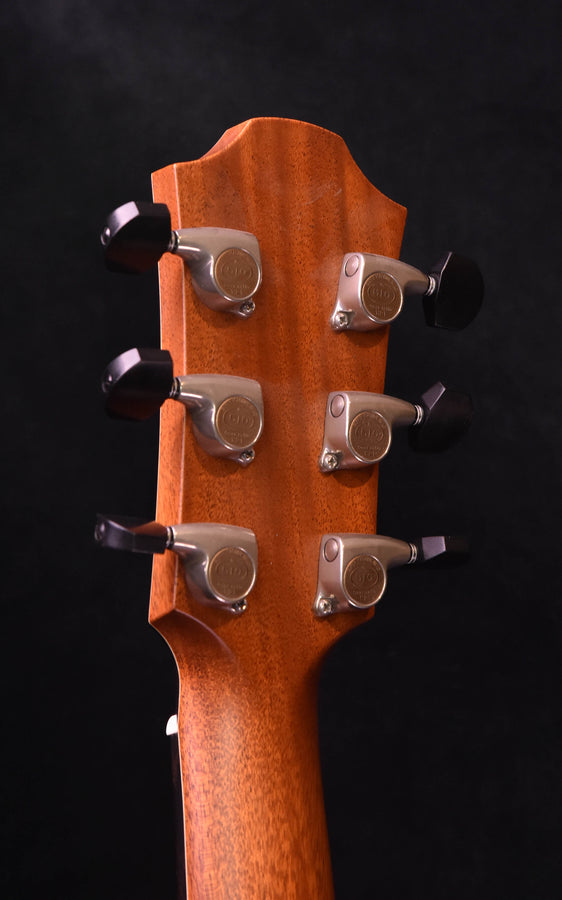 Acoustic guitar headstock with six chrome tuning pegs, natural wood grain