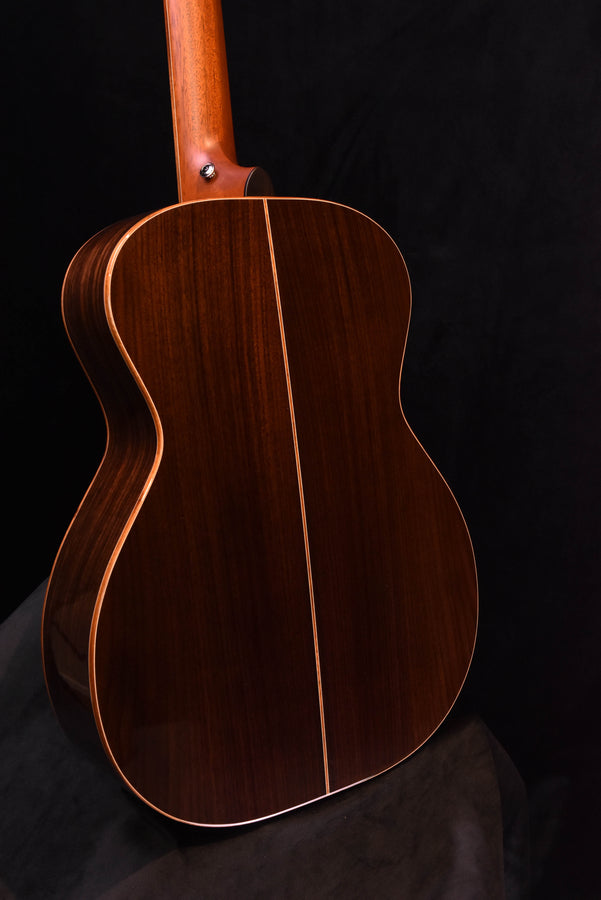 Used acoustic guitar back view with dark wood grain and light edge binding