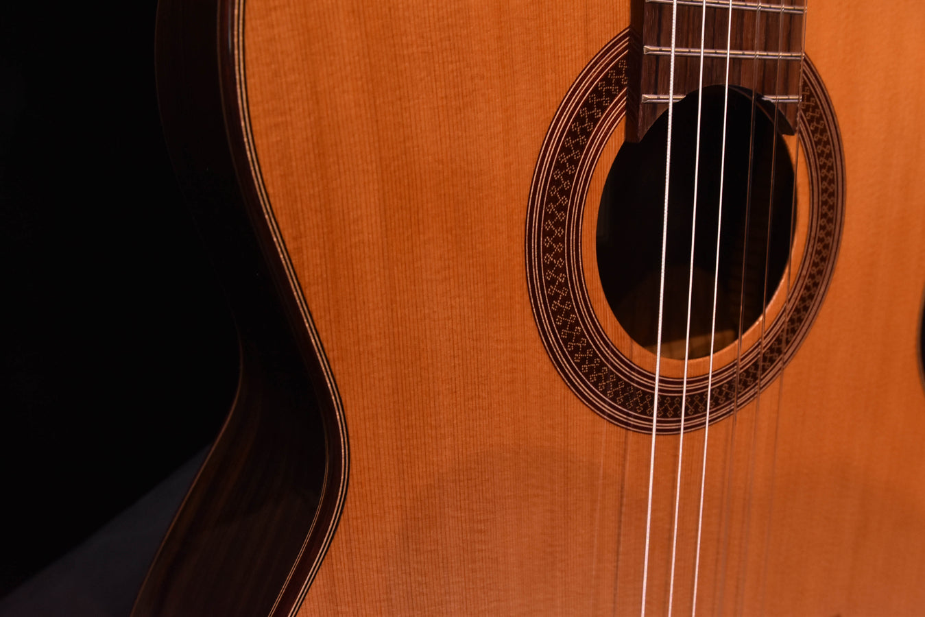 Sound hole rosette and strings on cedar-top classical guitar