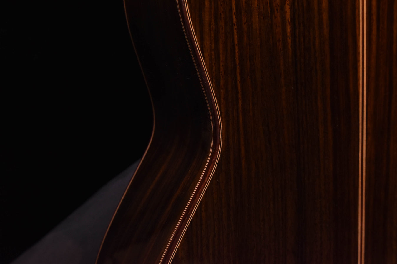 C7 cedar top classical guitar, side view of dark wood body with binding