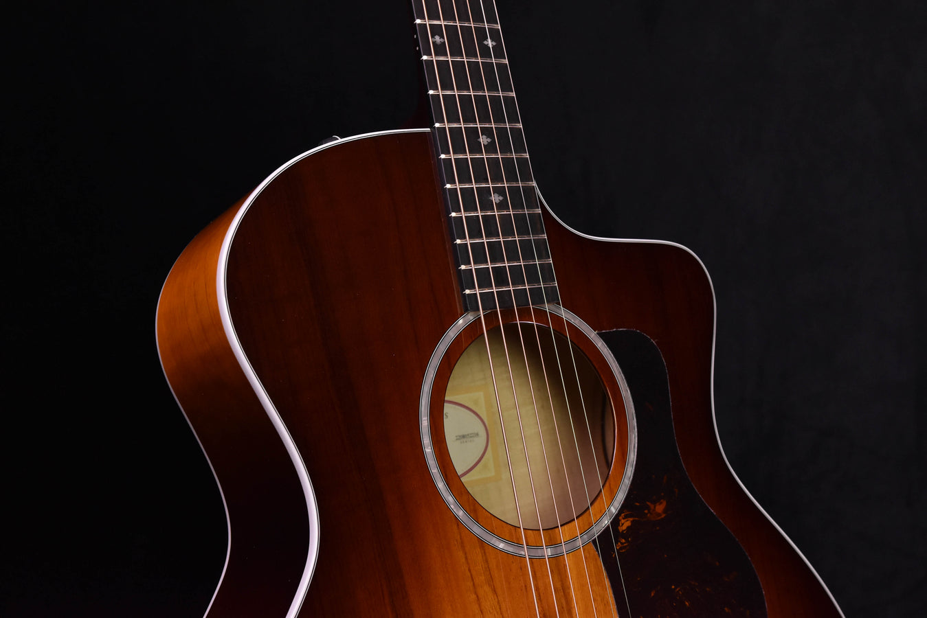 Acoustic-electric guitar with circular rosette around sound hole and pickguard area, close view