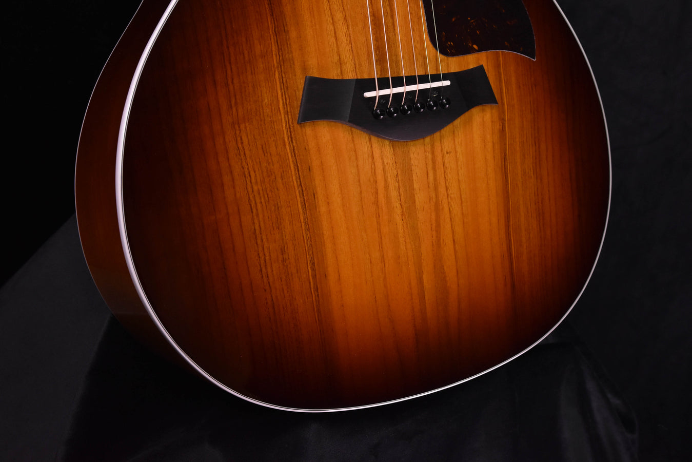 Acoustic-electric guitar front, black pickguard and bridge with strings, close-up
