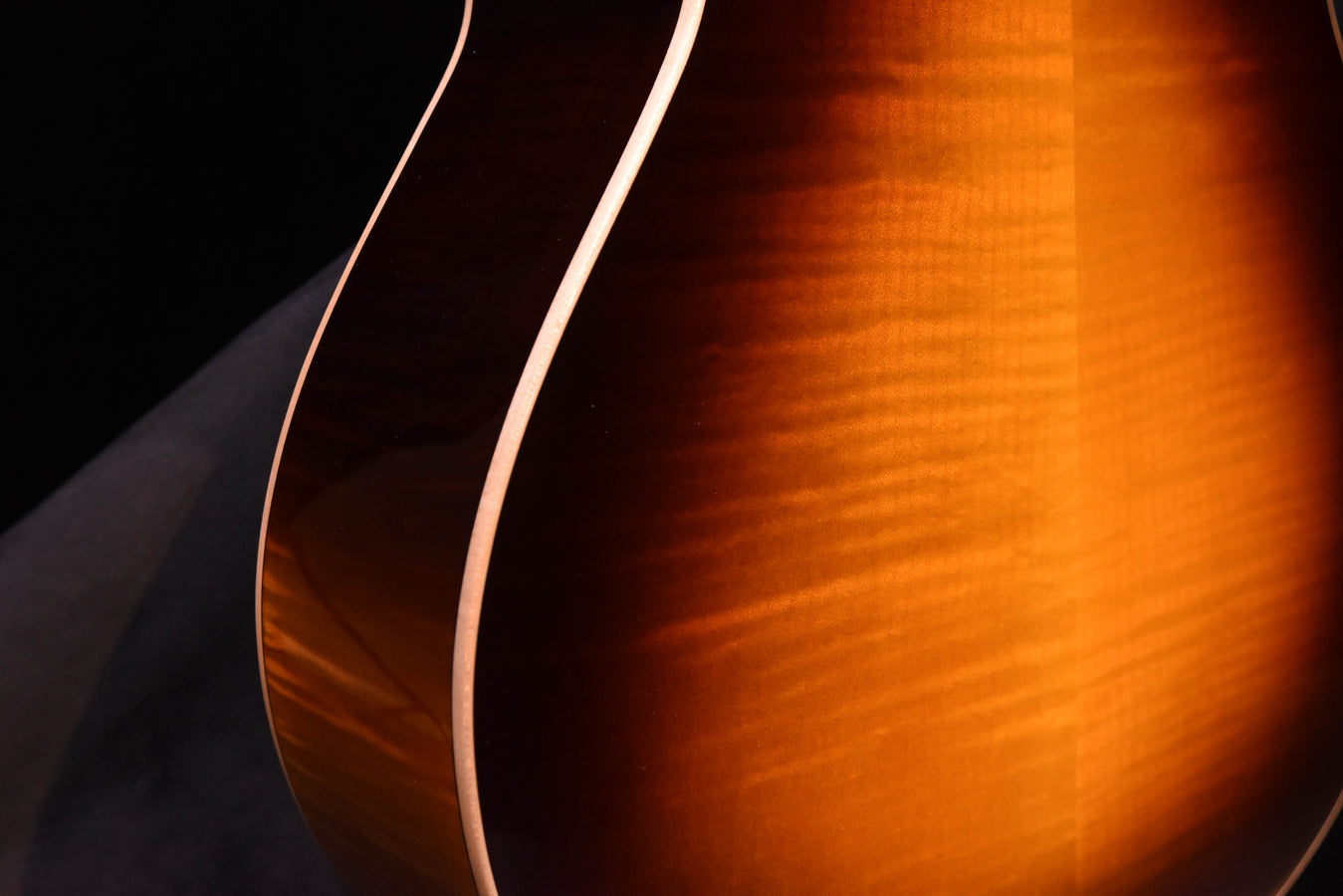 Tobacco sunburst acoustic guitar side with visible wood grain and curved bout