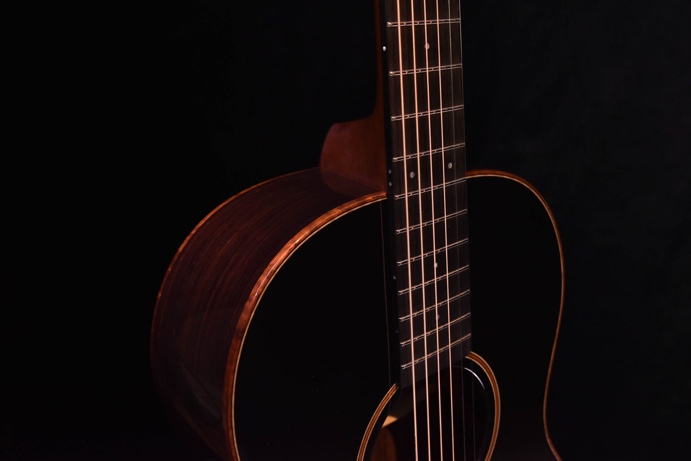 Acoustic guitar close-up showing dark top edge and upper bout with neck