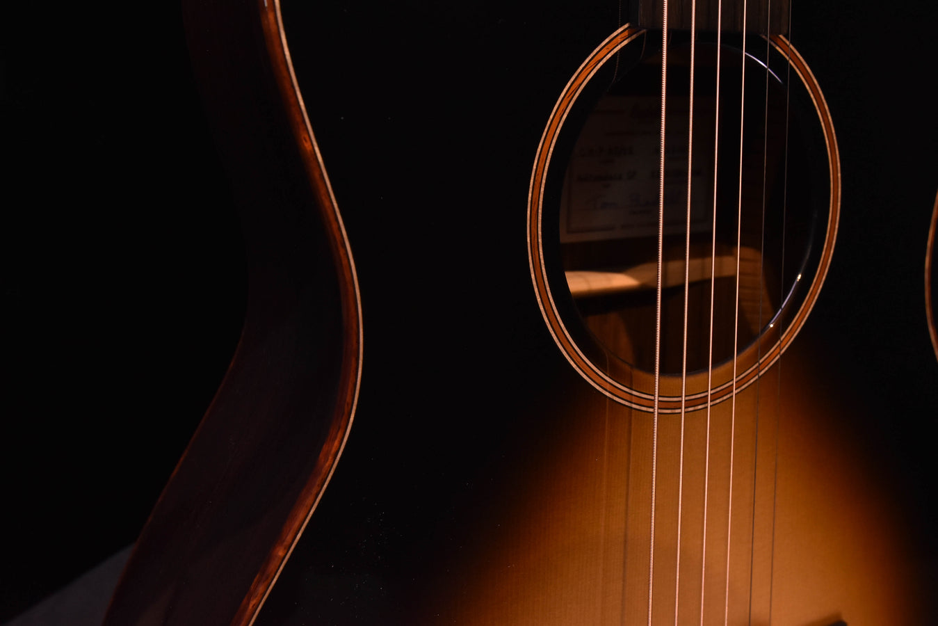 Acoustic guitar sound hole and strings with glossy dark finish on the lower bout
