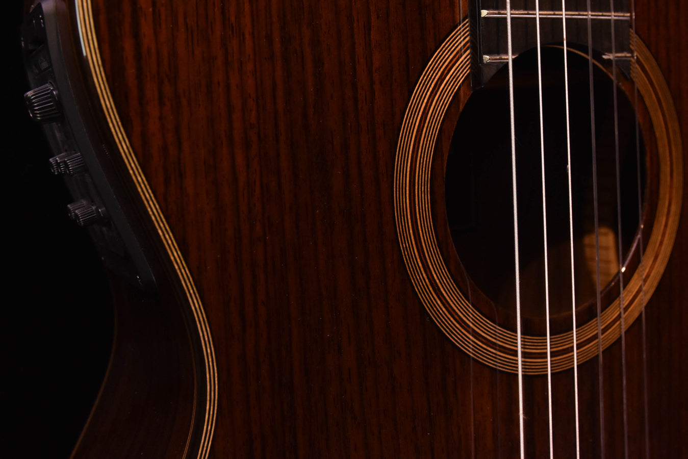 Close-up of soundhole rosette and binding lines on a natural brown guitar body
