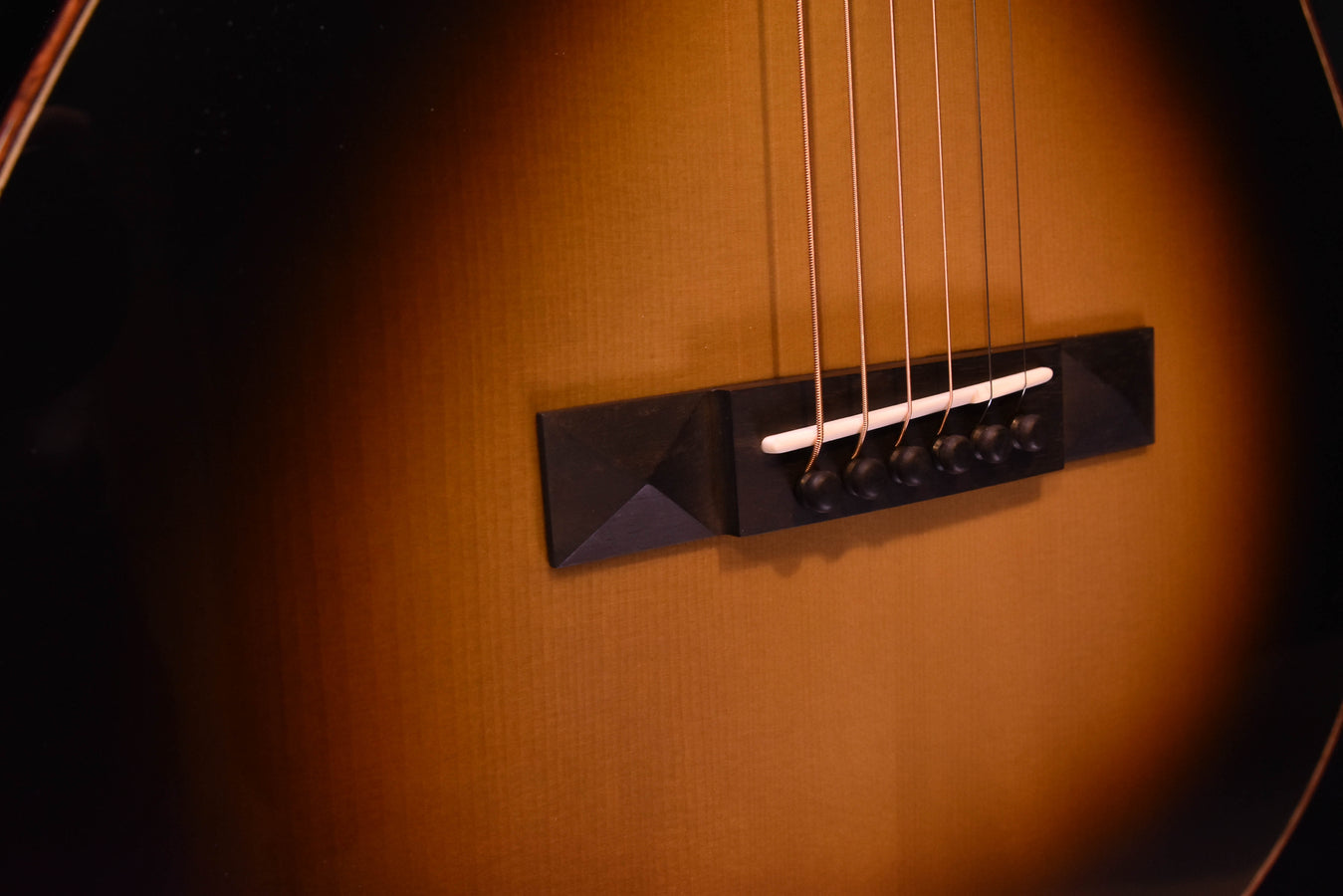Acoustic guitar bridge area with black bridge plate and steel strings
