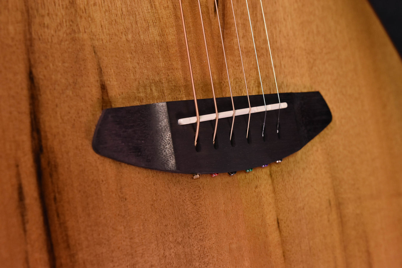 Akustische Gitarre, Nahaufnahme Stegplatte mit Saiten über dunkler Brücke
