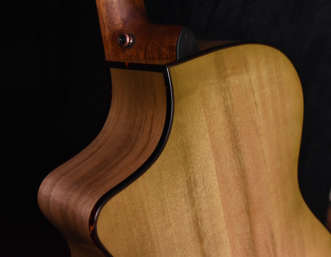 Natural wood concert guitar body with dark binding around the soundhole